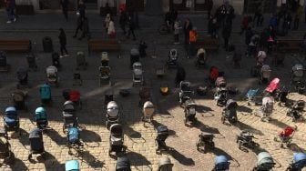 Ratusan kereta dan keranjang bayi kosong di pajang di luar gedung dewan kota di Lviv, Ukraina, Jumat (18/3/2022). [Yuriy Dyachyshyn / AFP]
