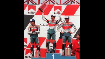 Tadayuki Okada dari Tim Repsol Honda Jepang (tengah) mengangkat trofi di podium dengan tempat kedua Mick Doohan dari tim Repsol Honda Australia (kanan) dan Alex Criville dari tim Repsol Honda Spanyol (kiri) di Kejuaraan Dunia Marlboro Indonesia Grand balapan di sirkuit Sentul, 28 September 1997. [KEMAL JUFRI / AFP] 