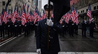 Petugas dari New York Fire Department (FDNY) memegang bendera Amerika Serikat ketika mereka berbaris saat parade perayaan Hari St. Patrick di New York, Amerika Serikat, Kamis (17/3/2022). [Ed JONES / AFP]