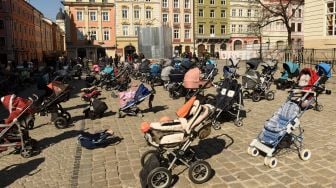 Ratusan kereta dan keranjang bayi kosong di pajang di luar gedung dewan kota di Lviv, Ukraina, Jumat (18/3/2022). [Yuriy Dyachyshyn / AFP]
