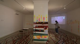 Pengunjung mengamati karya seni dalam pameran tunggal karya Otty Widasary yang bertajuk "Partisan" di Gedung D, Galeri Nasional, Jakarta, Minggu (20/3/2022). [Suara.com/Angga Budhiyanto]