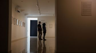 Pengunjung mengamati karya seni dalam pameran tunggal karya Otty Widasary yang bertajuk "Partisan" di Gedung D, Galeri Nasional, Jakarta, Minggu (20/3/2022). [Suara.com/Angga Budhiyanto]