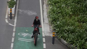 Pesepeda melintasi jalur khusus sepeda di Jalan Jenderal Sudirman, Jakarta, Minggu (20/3/2022). [Suara.com/Angga Budhiyanto]