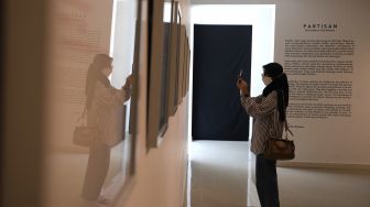 Pengunjung mengambil gambar  karya seni dalam pameran tunggal karya Otty Widasary yang bertajuk "Partisan" di Gedung D, Galeri Nasional, Jakarta, Minggu (20/3/2022). [Suara.com/Angga Budhiyanto]