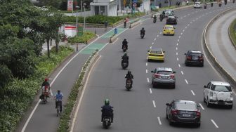 Pesepeda melintasi jalur khusus sepeda di Jalan Jenderal Sudirman, Jakarta, Minggu (20/3/2022). [Suara.com/Angga Budhiyanto]