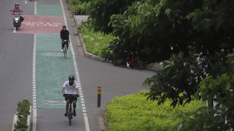 Pesepeda melintasi jalur khusus sepeda di Jalan Jenderal Sudirman, Jakarta, Minggu (20/3/2022). [Suara.com/Angga Budhiyanto]