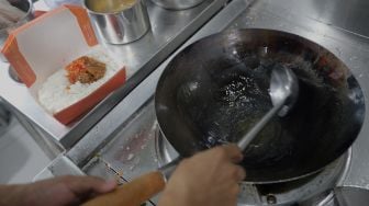 Juru masak memanaskan minyak goreng untuk membuat nasi goreng pesanan pelanggan di salah satu gerai di kawasan Ampera, Jakarta, Senin (21/3/2022). [Suara.com/Angga Budhiyanto]