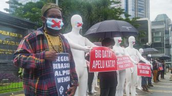 Sejumlah aktivis mengenakan masker bertanda silang melakukan aksi di depan Polda Metro Jaya, Jakarta Selatan, Senin (21/3/2022). [Suara.com/Alfian Winanro]