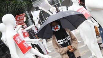 Sejumlah aktivis mengenakan masker berjalan diantara boneka manekin yang dipajang saat melakukan aksi di depan Polda Metro Jaya, Jakarta Selatan, Senin (21/3/2022). [Suara.com/Alfian Winanro]