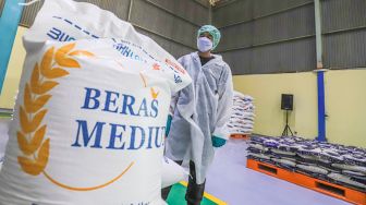 Pekerja mengoperasikan mesin Rice To Rice (RTR) untuk mengisi karung beras medium di Gudang RTT Bulog, Kelapa Gading, Jakarta Utara, Rabu (23/3/2022). [Suara.com/Alfian Winanto]