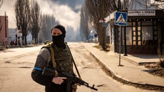 Seorang prajurit Ukraina berjaga di dekat gudang yang terbakar akibat dihantam rudal Rusia di pinggiran kota Kyiv, Ukraina, kamis (24/3/2022). [FADEL SENNA / AFP]
