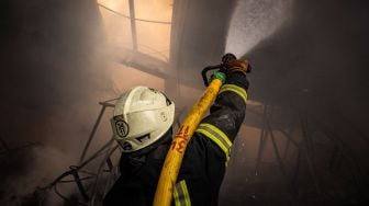 Petugas pemadam kebakaran memadamkan api di gudang yang terbakar akibat dihantam rudal Rusia di pinggiran kota Kyiv, Ukraina, kamis (24/3/2022). [FADEL SENNA / AFP]
