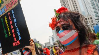 Seorang massa demonstrasi merias wajahnya saat mengikuti aksi darurat iklim di Jalan Sudirman, Jakarta Pusat, Jumat (25/3/2022). [Suara.com/Alfian Winanto]