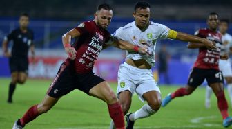 Pesepak bola Bali United Ilija Spasojevic (kiri) berebut bola dengan pesepak bola Persebaya Surabaya Arif Satria (kanan) saat pertandingan Liga 1 di Stadion I Gusti Ngurah Rai, Denpasar, Bali, Jumat (25/3/2022). [ANTARA FOTO/Fikri Yusuf/rwa]
