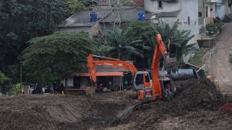 Pekerja menggunakan alat berat mengeruk lahan yang akan dijadikan Waduk Brigif, Jagakarsa, Jakarta, Minggu (27/3/2022). [Suara.com/Angga Budhiyanto]