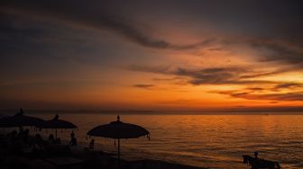 Pengunjung menikmati pemandangan matahari terbenam di pantai Tanjung Bias, Desa Senteluk, Kecamatan Batulayar, Lombok Barat, NTB, Sabtu (26/3/2022). ANTARA FOTO/Ahmad Subaidi