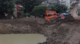 Pekerja menggunakan alat berat mengeruk lahan yang akan dijadikan Waduk Brigif, Jagakarsa, Jakarta, Minggu (27/3/2022). [Suara.com/Angga Budhiyanto]