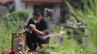 Presenter Vicky Prasetyo berdoa di samping makam ibunda Kalina Oktarani, Erlan Wardhania di TPU Taman Abadi, Ciputat, Tangerang Selatan, Banten, Senin (28/3/2022). [Suara.com/Angga Budhiyanto]