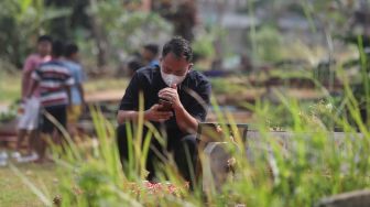 Presenter Vicky Prasetyo berdoa di samping makam ibunda Kalina Oktarani, Erlan Wardhania di TPU Taman Abadi, Ciputat, Tangerang Selatan, Banten, Senin (28/3/2022). [Suara.com/Angga Budhiyanto]