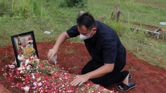 Presenter Vicky Prasetyo menyiramkan air kembang ke makam ibunda Kalina Oktarani, Erlan Wardhania di TPU Taman Abadi, Ciputat, Tangerang Selatan, Banten, Senin (28/3/2022). [Suara.com/Angga Budhiyanto]