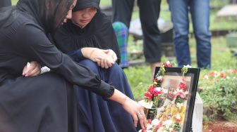 Kalina Oktarani berdoa di samping makam sang ibunda Erlan Wardhania di TPU Taman Abadi, Ciputat, Tangerang Selatan, Banten, Senin (28/3/2022). [Suara.com/Angga Budhiyanto]