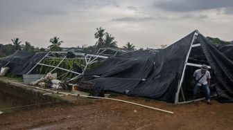 Warga membereskan atap baja ringan yang roboh setelah diterjang angin puting beliung di Desa Dewasari, Kabupaten Ciamis, Jawa Barat, Selasa (29/3/2022).  ANTARA FOTO/Adeng Bustomi