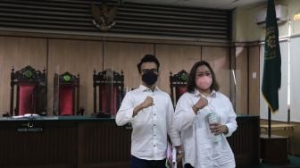 Terdakwa Adam Deni (kiri) dan Ni Made Dwita Anggari bersiap mengikuti sidang dengan agenda pembacaan putusan sela kasus pelanggaran Undang-Undang ITE di Pengadilan Negeri Jakarta Utara, Jakarta, Selasa (29/3/2022). [Suara.com/Angga Budhiyanto]