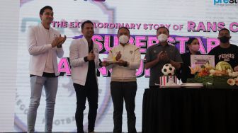 Raffi Ahmad (kedua kiri) memberikan potongan tumpeng pada Menteri Pemuda dan Olahraga Zainudin Amali (ketiga kiri) saat acara "Superstar Announcement RANS Cilegon FC" di kantor Prestige Motorcars, Pluit, Jakarta, Selasa (29/3/2022). [Suara.com/Angga Budhiyanto]