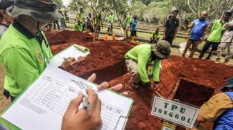 Juri memberikan penilaian dalam lomba gali kubur di TPU Pondok Rajeg, Kabupaten Bogor, Jawa Barat, Selasa (29/3/2022).  ANTARA FOTO/Yulius Satria Wijaya
