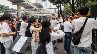 Komposer Addie MS menjadi konduktor orkestra saat menggelar seruan aksi damai di Depan Kedutaan Besar Rusia di Kuningan, Jakarta Selatan, Rabu (30/2/2022). [Suara.com/Alfian Winanto]