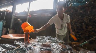 Pekerja menuang dodol betawi ke dalam wadah di rumah produksi Dodol Betawi Sari Rasa Ibu Yuyun, Jakarta Selatan, Kamis (31/3/2022). [Suara.com/Alfian Winanto]