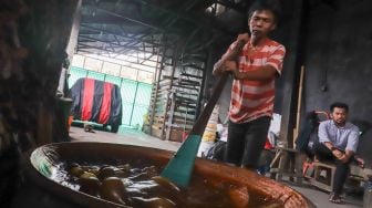 Pekerja mengaduk dodol betawi di dalam kuali di rumah produksi Dodol Betawi Sari Rasa Ibu Yuyun, Jakarta Selatan, Kamis (31/3/2022). [Suara.com/Alfian Winanto]