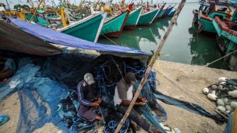 Dua nelayan memperbaiki jaring di TPI Pusong, Lhokseumawe, Aceh, Kamis (31/3/2022). ANTARA FOTO/Rahmad
