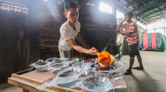 Pekerja menuang dodol betawi ke dalam wadah di rumah produksi Dodol Betawi Sari Rasa Ibu Yuyun, Jakarta Selatan, Kamis (31/3/2022). [Suara.com/Alfian Winanto]