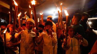 Sejumlah warga dan anak-anak mengikuti pawai obor di Menteng, Jakarta Pusat, Kamis (31/3/2022). [Suara.com/Alfian Winanto]