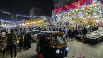 Sebuah kendaraan tuk-tuk melewati pasar yang menjual lentera dan dekorasi Ramadhan lainnya di distrik Sayyida Zeinab, Kairo, Mesir, Rabu (30/3/2022). [Khaled DESOUKI / AFP]