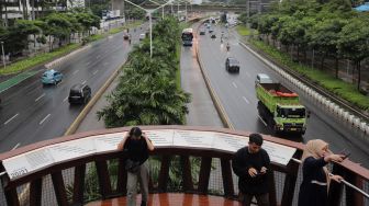 Warga berfoto di Jembatan Penyeberangan Orang (JPO) Pinisi Karet-Sudirman, Jakarta, Minggu (3/4/2022). [Suara.com/Angga Budhiyanto]