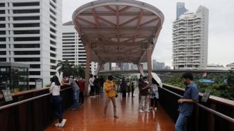 Warga menikmati suasana di Jembatan Penyeberangan Orang (JPO) Pinisi Karet-Sudirman, Jakarta, Minggu (3/4/2022). [Suara.com/Angga Budhiyanto]