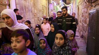 Warga Palestina berjalan menyusuri jalan di Kota Tua Yerusalem, Sabtu (2/4/2022). [Menahem KAHANA / AFP]
