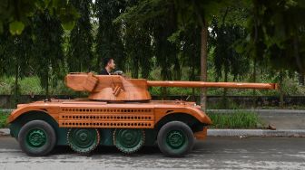 Truong Van Dao menaiki tank kayu yang dibuatnya dari minibus tua di sebuah daerah perumahan di provinsi Bac Ninh, Vietnam, Senin (28/3/2022). [Nhac NGUYEN / AFP]