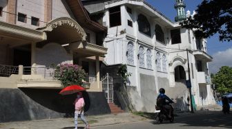 
Warga melintasi Gereja Pantekosta Bukit Zaitun (kiri) dan Masjid Dakwah Wanita (kanan) di Kendari, Sulawesi Tenggara, Selasa (5/4/2022).  ANTARA FOTO/Jojon