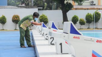 Petugas membersihkan dan merawat area kolam renang di Gelanggang Remaja Jakarta Selatan (GRJS) Bulungan, Kebayoran Baru, Jakarta Selatan, Rabu (6/4/2022). [Suara.com/Alfian Winanto]