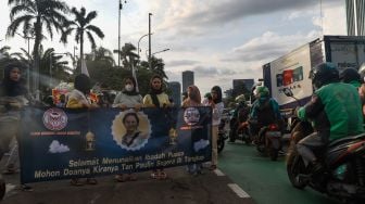 Massa memajang spanduk dengan foto Tan Paulin saat menggelar aksi demonstrasi di depan Gedung DPR RI, Jakarta Pusat, Rabu (6/4/2022). [Suara.com/Alfian Winanto]