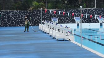 Petugas membersihkan dan merawat area kolam renang di Gelanggang Remaja Jakarta Selatan (GRJS) Bulungan, Kebayoran Baru, Jakarta Selatan, Rabu (6/4/2022). [Suara.com/Alfian Winanto]