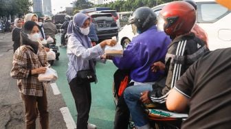 Massa membagikan Takjil pada pengendara saat menggelar aksi demonstrasi menuntut proses hukum Tan Paulin di depan Gedung DPR RI, Jakarta Pusat, Rabu (6/4/2022). [Suara.com/Alfian Winanto]