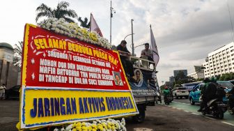 Massa memajang karangan bunga dengan foto Tan Paulin saat menggelar aksi demonstrasi di depan Gedung DPR RI, Jakarta Pusat, Rabu (6/4/2022). [Suara.com/Alfian Winanto]