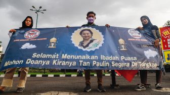 Massa memajang spanduk dengan foto Tan Paulin saat menggelar aksi demonstrasi di depan Gedung DPR RI, Jakarta Pusat, Rabu (6/4/2022). [Suara.com/Alfian Winanto]