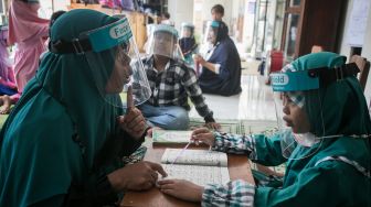 Guru mengajari siswa penyandang tuna rungu membaca Iqra dengan metode membaca gerak bibir saat mengikuti kegiatan Pesantren Kilat Ramadhan Tuna Rungu di SLB B Prawestri, Karanganyar, Jawa Tengah, Kamis (7/4/2022).  ANTARA FOTO/Mohammad Ayudha
