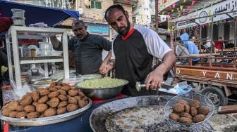 Pedagang menggoreng Falafel untuk dijual saat bulan Ramadhan di Gaza, Palestina, Minggu (3/4/2022). [MOHAMMED ABED / AFP]