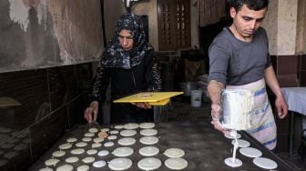 Pedagang memasak Qatayef (pangsit tradisional Arab) untuk dijual saat bulan Ramadhan di Gaza, Palestina, Minggu (3/4/2022). [MOHAMMED ABED / AFP]
